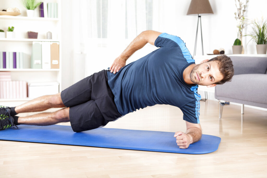 Judith Arnhard Beckenbodentraining für den Mann - Bild von einem Mann, der sich auf einer Matte im Wohnzimmer im Side Plank stützt- Vielfältiges Kursangebot