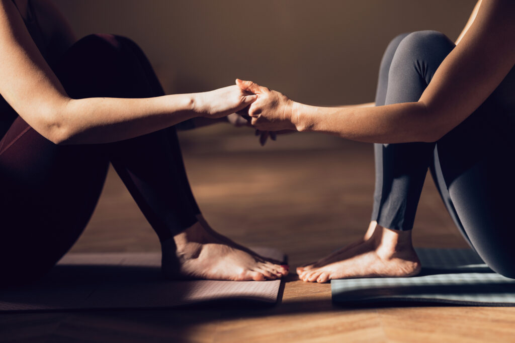 Judith Arnhard Beckenbodentraining für die Frau - Nahaufnahme von zwei Frauen, die eine Partner Yoga-Pose machen - Vielfältiges Kursangebot